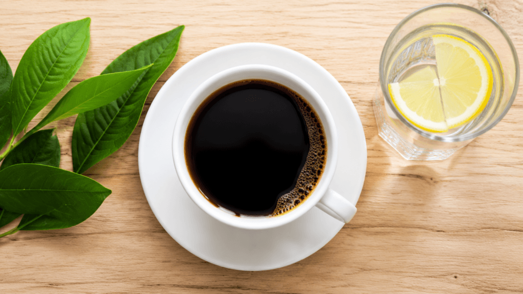 Xícara de café preto e copo de água com limão, mostrando líquidos permitidos no jejum intermitente.