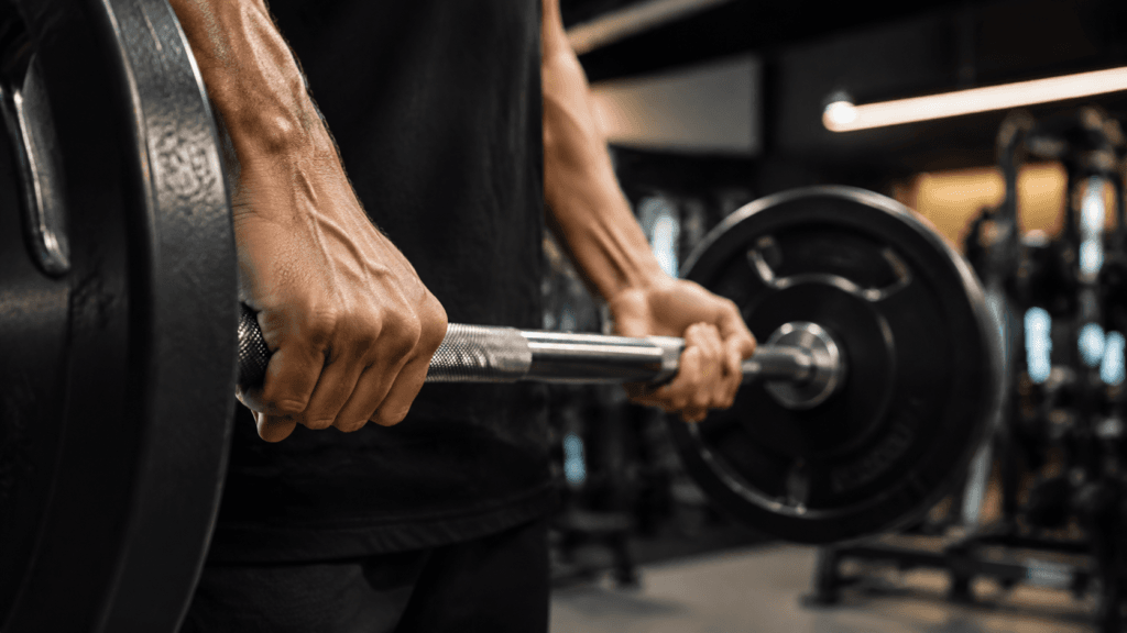 Mãos segurando barra de musculação em foco, representando o treino de força.